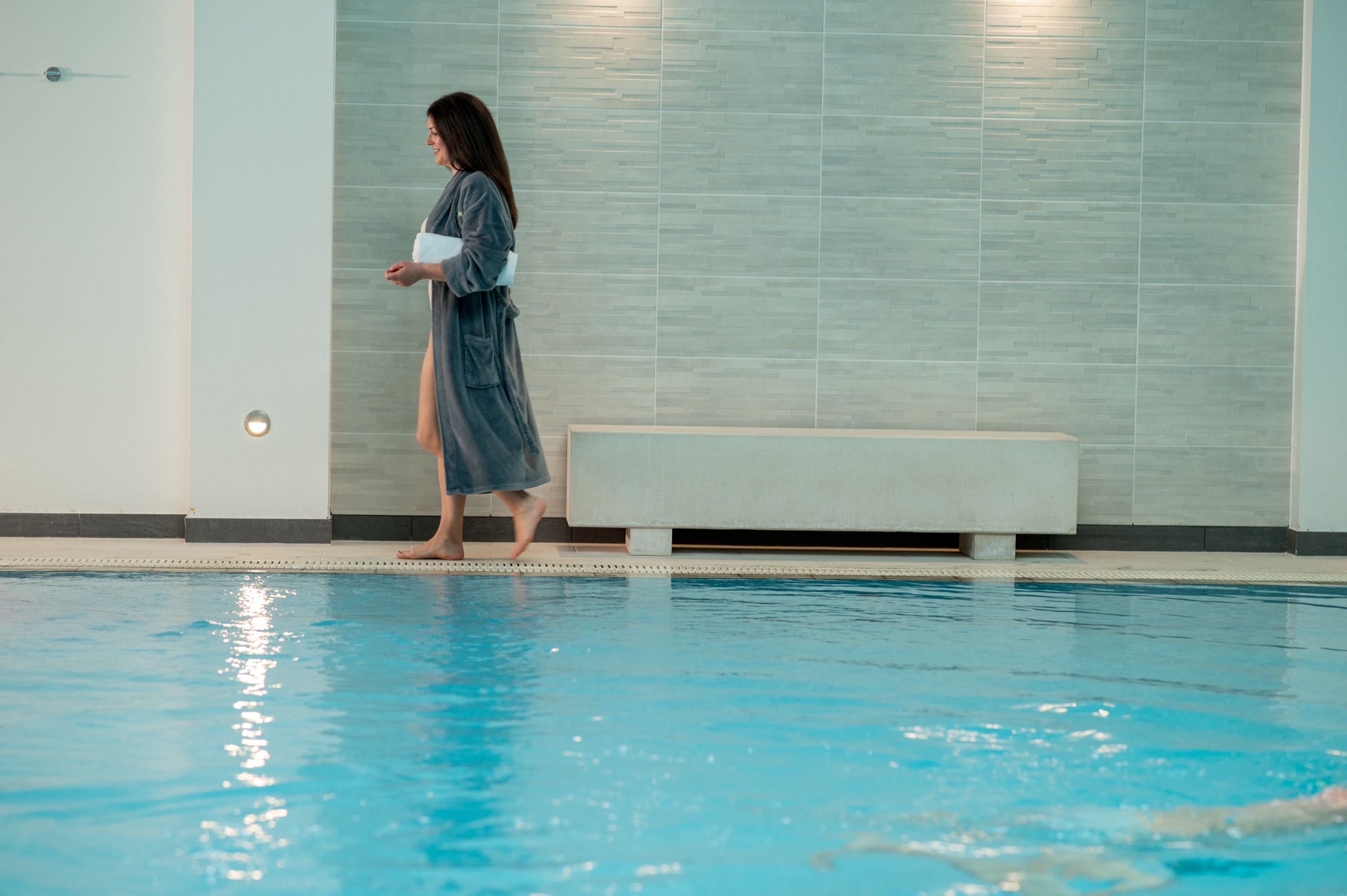 Woman walking left by the pool in spa robe